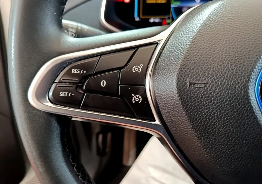 Gros plan sur les commandes du régulateur de vitesse au volant cuir noir de la Renault ZOE Business R110 blanche de 2021.
