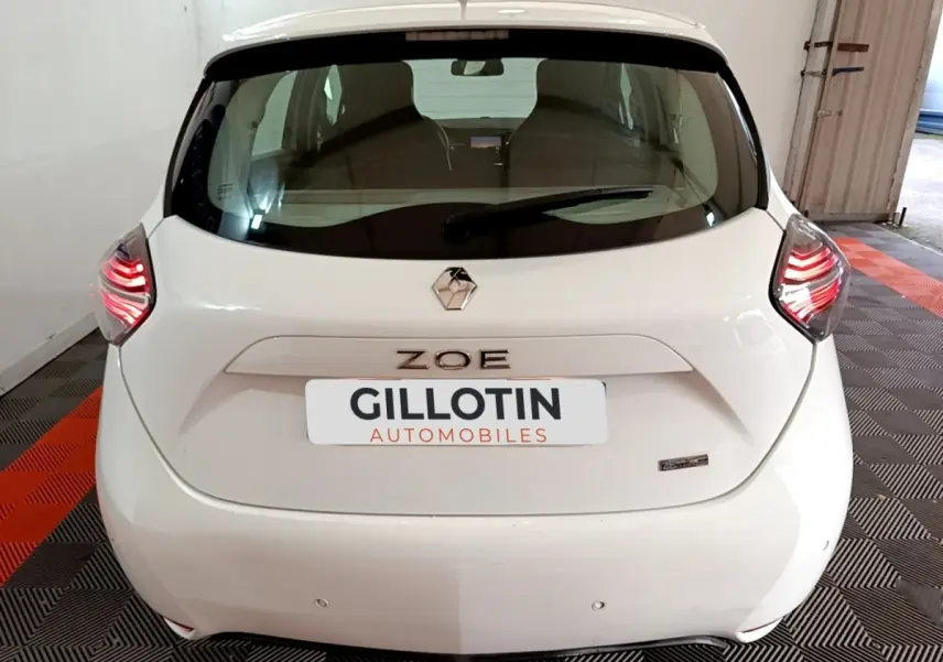 Vue arrière d'une Renault ZOE blanche 2021 avec feux LED allumés et logo ZOE bien visible.