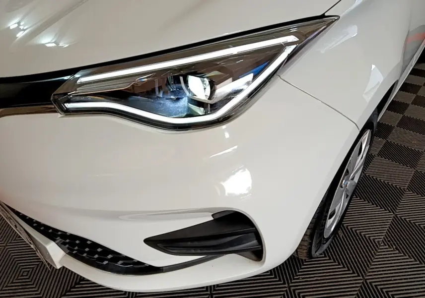 Gros plan sur le phare avant droit blanc de la Renault ZOE Business R110, avec détails du pare-chocs et roue.