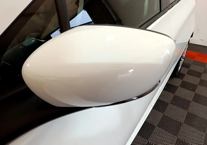 Gros plan sur le rétroviseur côté gauche d'une Renault ZOE Business R110 blanc, avec partie latérale visible.