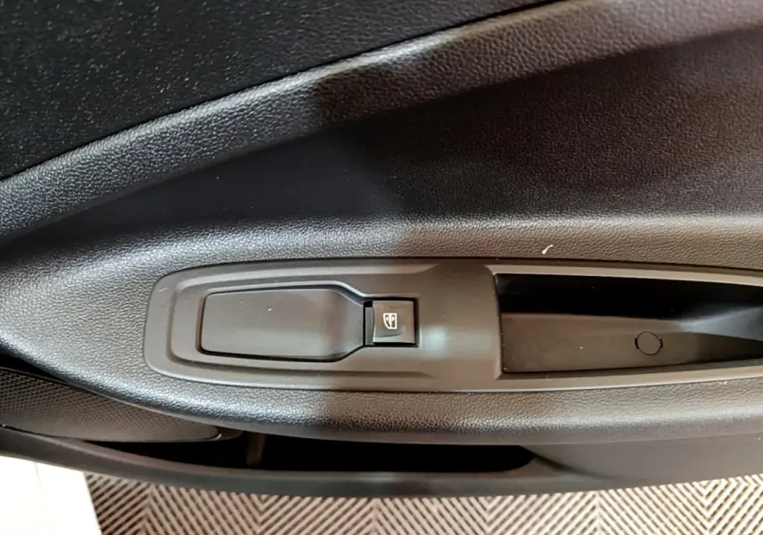 Gros plan sur la commande de lève-vitre côté gauche de la porte intérieure d'une Renault ZOE blanche de 2021.