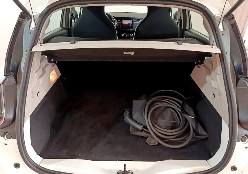 Coffre ouvert d'une Renault ZOE Business R110 blanche, vue arrière avec câble de recharge visible à l'intérieur.