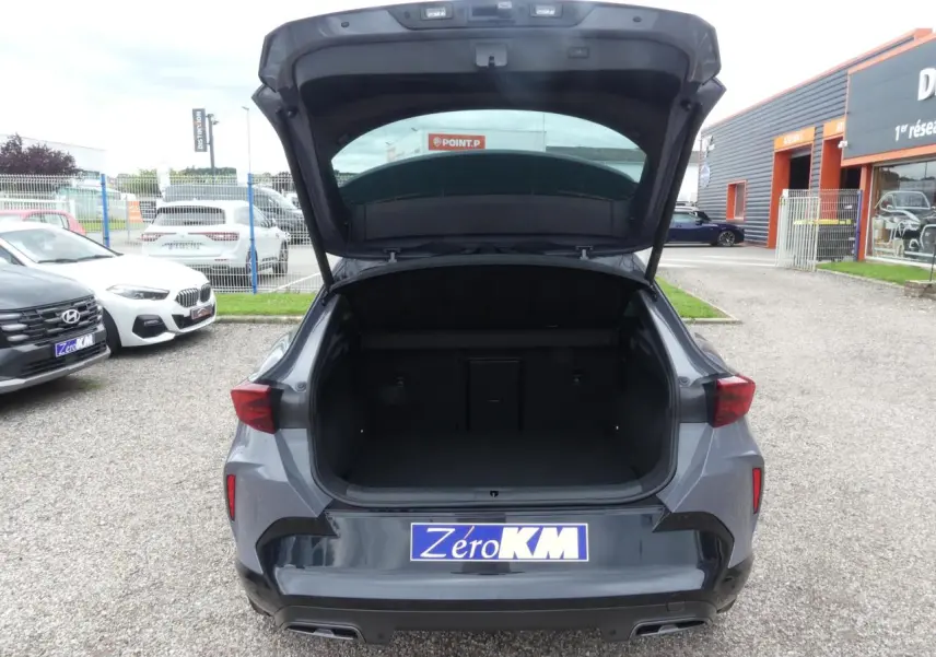 Vue arrière ouverte du CUPRA Formentor gris Graphène avec coffre spacieux et feux arrière triangulaires allumés.