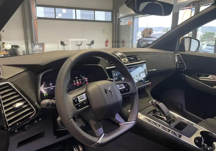 Vue intérieure côté conducteur du DS7 Crossback gris titanium, mettant en valeur le volant cuir perforé et l'écran tactile central.