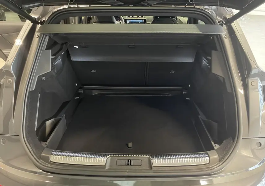 Coffre ouvert vu de l'arrière d'un DS7 Crossback gris titanium avec seuil de coffre chromé et intérieur noir.
