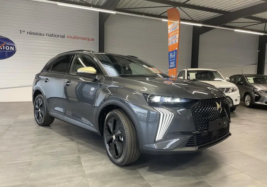DS7 Crossback gris titanium en 3/4 avant droit avec calandre noire et feux LED distinctifs en showroom.