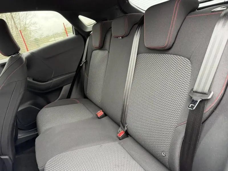 Vue intérieure de la banquette arrière du Ford Puma 2024, tissu noir avec surpiqûres rouges et ceintures grises.