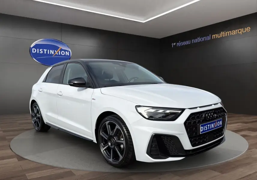 Audi A1 Sportback blanc à toit noir en 3/4 avant droit, avec jantes 18 pouces noires et calandre noire distinctive.