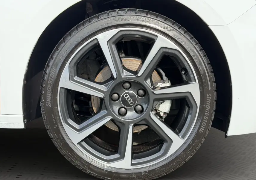 Gros plan sur la jante 18 pouces bicolore Audi Sport en hélice d'une Audi A1 Sportback blanche.