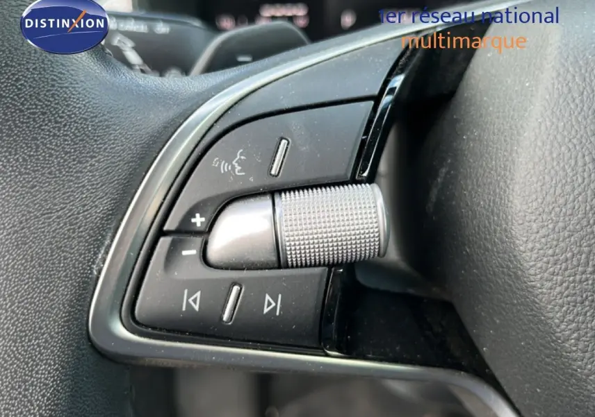 Gros plan sur les commandes de volume et multimédia au volant d’une Skoda Scala gris magnétique, finition 2025.