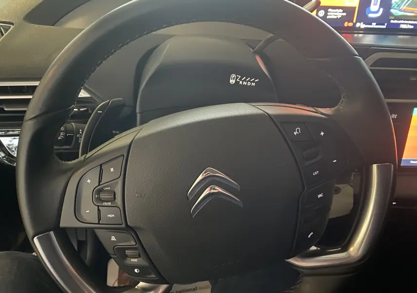 Volant noir de Citroën Grand C4 Spacetourer 2022, vue rapprochée centrée sur commandes intégrées et logo chromé.