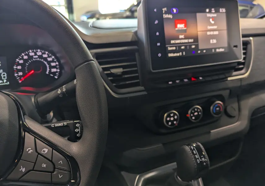 Vue intérieure du tableau de bord du Renault Trafic Fourgon 2025, avec volant, écran tactile et levier de boîte automatique.