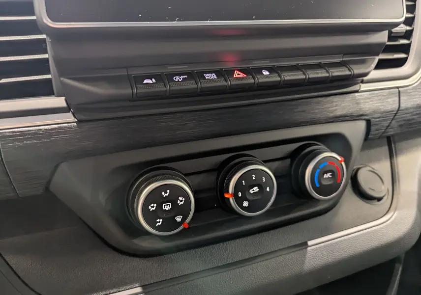 Gros plan sur les commandes de climatisation et boutons fonctionnels du tableau de bord du Renault Trafic Fourgon gris urbain 2025.