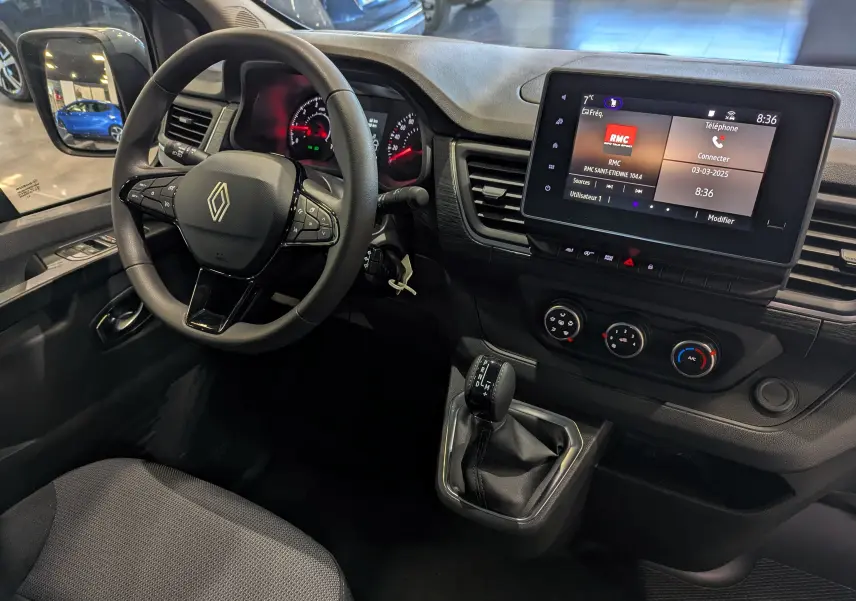 Vue intérieure côté conducteur du Renault Trafic Fourgon gris urbain 2025, avec volant multifonction et écran tactile central.