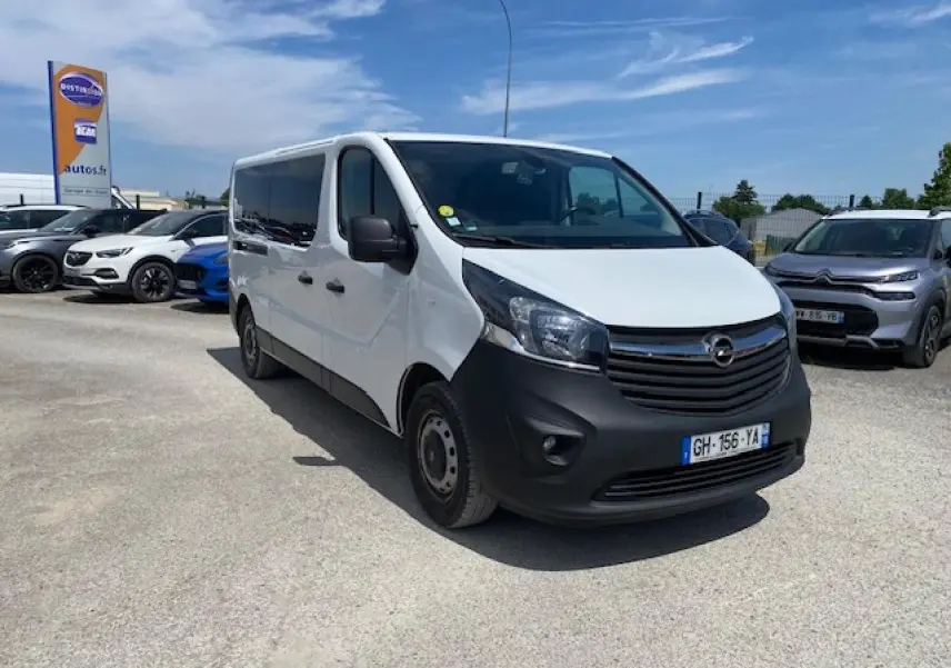 Opel Vivaro blanc vu en 3/4 avant droit, avec calandre noire et pare-chocs avant mat, stationné en extérieur.