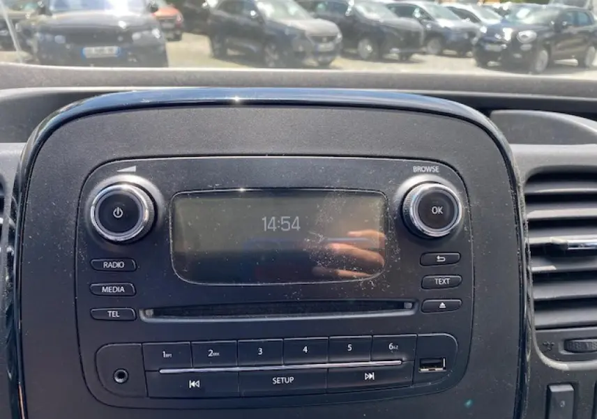 Console centrale de l'Opel Vivaro 2018 avec écran radio, boutons média et commandes intégrées, vue frontale rapprochée.