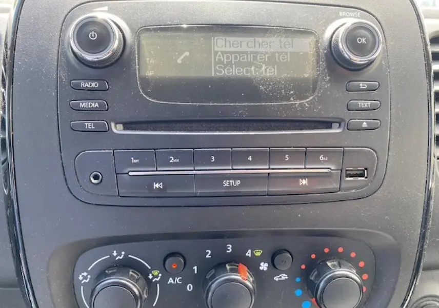 Vue rapprochée du tableau de bord de l'Opel Vivaro blanc 2018, mettant en valeur la radio et les commandes de climatisation.