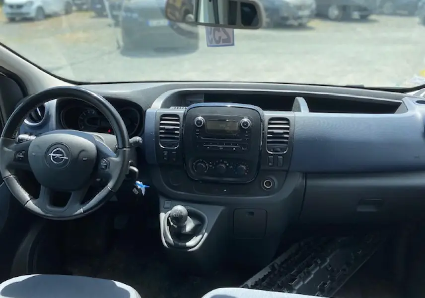 Vue intérieure du tableau de bord et volant d'un Opel Vivaro blanc 2018 avec boîte manuelle et commandes intégrées.