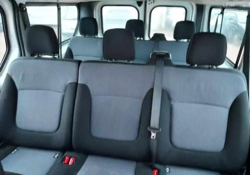 Vue intérieure des banquettes arrière grises et noires d'un Opel Vivaro blanc 9 places, montrant les appuie-têtes et ceinture de sécurité.