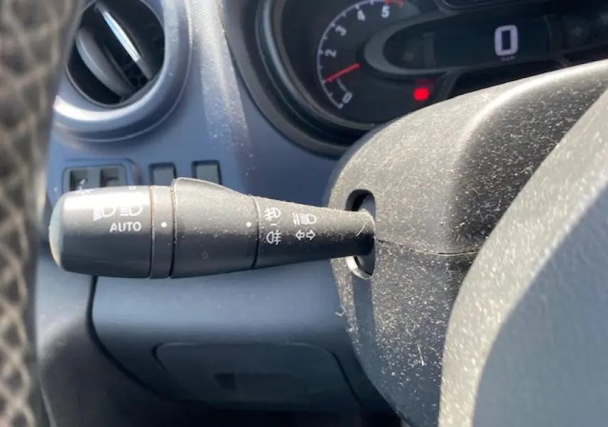 Gros plan sur la commande des phares automatiques à gauche du volant dans l'habitacle d'un Opel Vivaro blanc 2018.