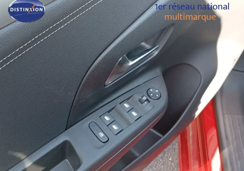 Gros plan sur la porte côté conducteur d'une Opel Corsa rouge Kardio métal avec commandes des vitres et poignée chrome.