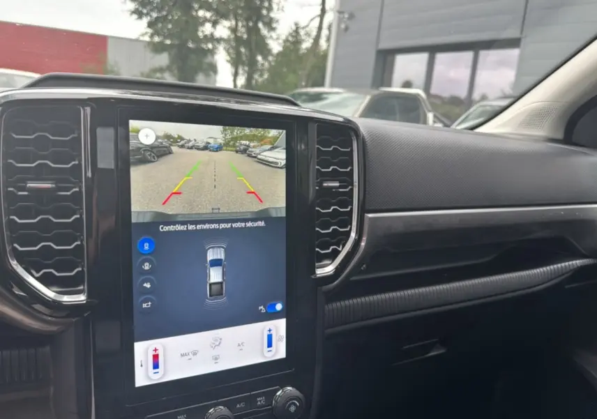 Vue intérieure centrée sur l'écran tactile vertical du Ford Ranger blanc glacier, affichant la caméra de recul et les commandes climatisation.