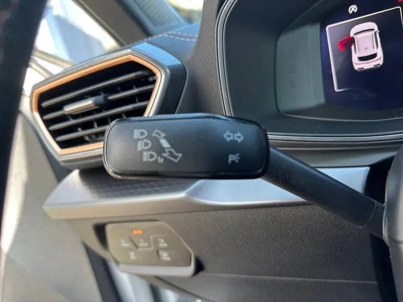 Gros plan sur la commande des feux et clignotants à gauche du volant dans l’habitacle du CUPRA Formentor blanc Nevada 2025.