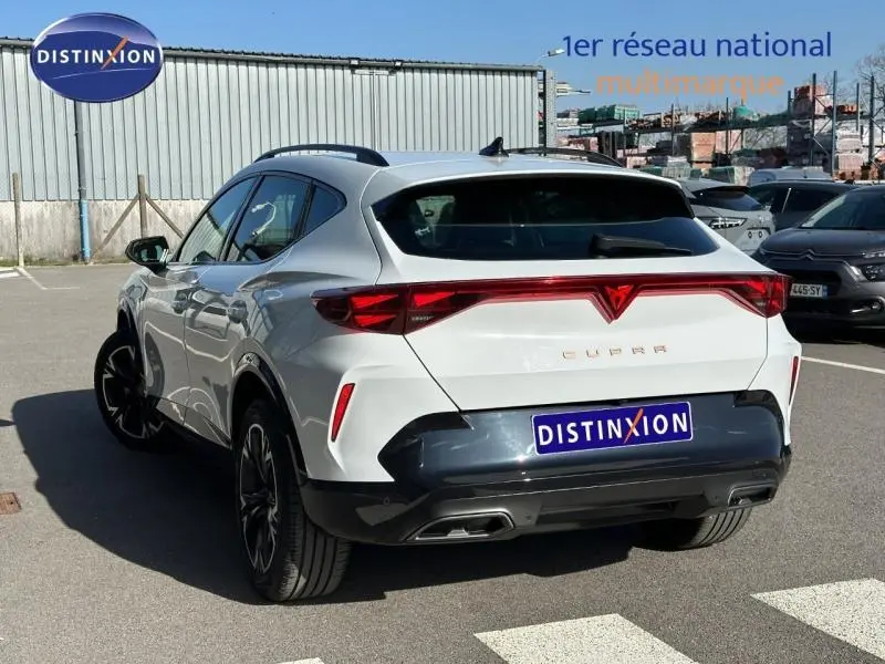 Vue 3/4 arrière droite d'un CUPRA Formentor blanc Nevada métallisé avec feux arrière reliés et double sortie d'échappement intégrée.