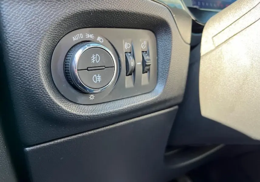 Gros plan sur les commandes d'éclairage intérieures noires de l'Opel Corsa 1.2i Turbo gris et noir, côté gauche du tableau de bord.