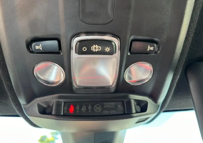 Vue en gros plan du plafonnier intérieur de l'Opel Corsa gris/noir, montrant les commandes d'éclairage et l'indicateur d'airbag passager.