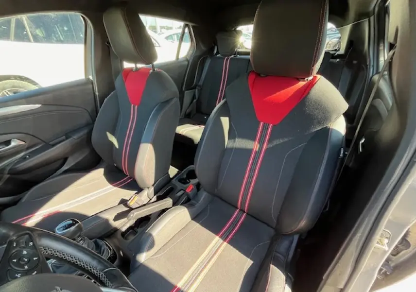 Vue intérieure avant droite de l'Opel Corsa 1.2i Turbo 2021 avec sièges sport noirs et rouges et volant cuir multifonction.