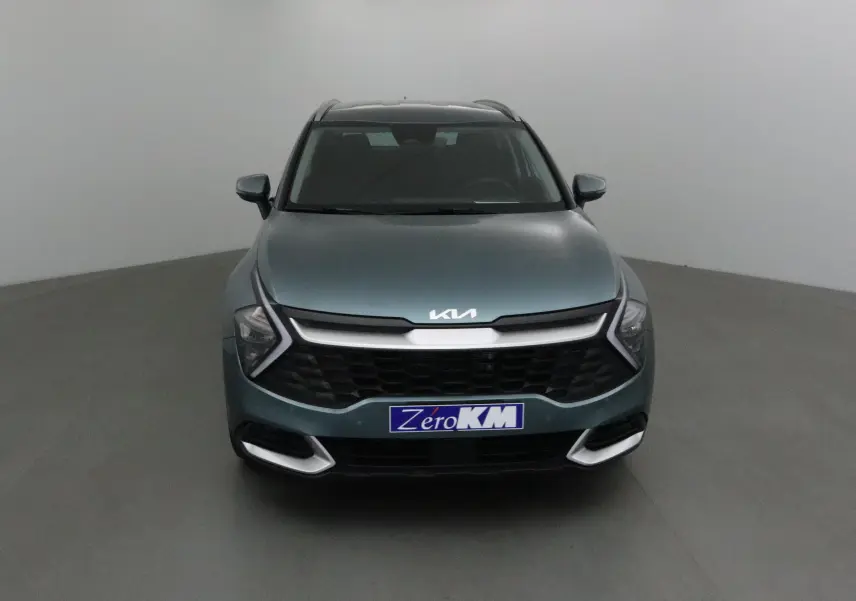 Vue frontale d'un KIA SPORTAGE gris Sirius 2025 avec calandre noire et logo KIA moderne lumineux.