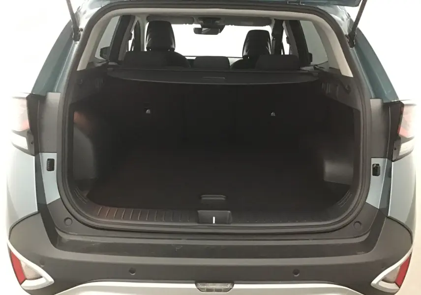 Coffre ouvert du Kia Sportage gris Sirius 2025, vue arrière montrant l'espace de chargement et les sièges arrière.