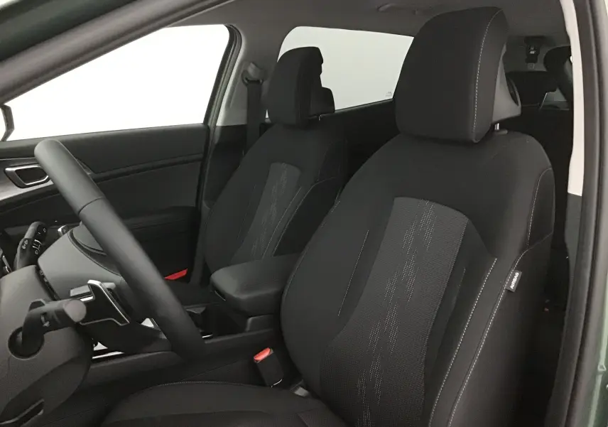Vue intérieure côté conducteur du Kia Sportage 2025, sièges noirs avec surpiqûres blanches et tissu central texturé.