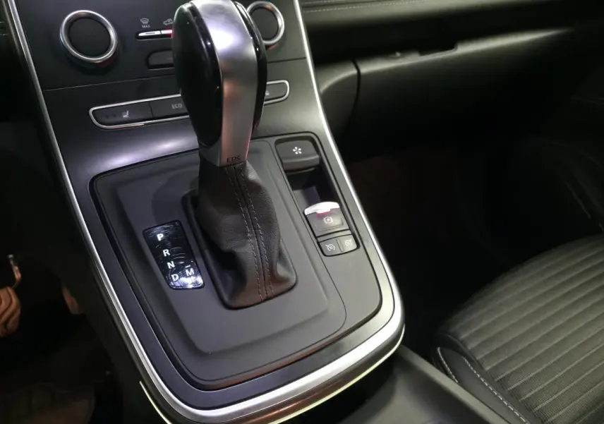 Gros plan sur la console centrale avec levier de vitesse automatique cuir et sièges noirs du Renault Scenic Grand Blanc.