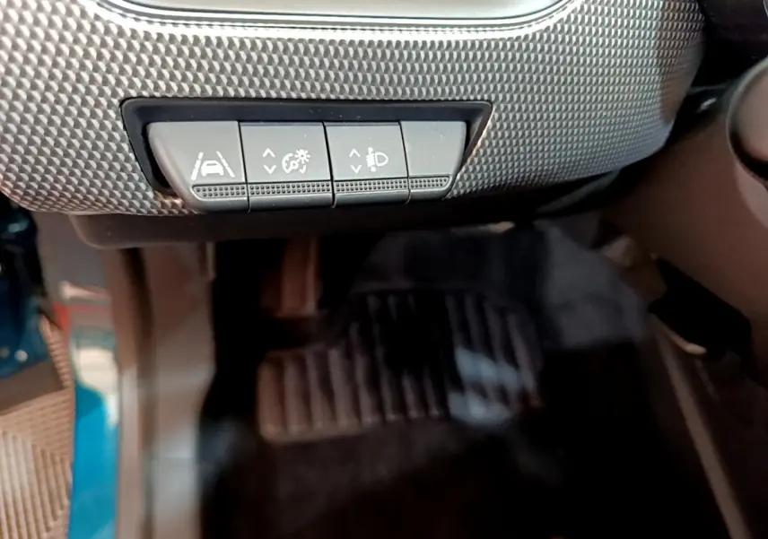 Gros plan sur les boutons de réglage d'assistance et éclairage sous le tableau de bord d'une Renault Arkana bleu.