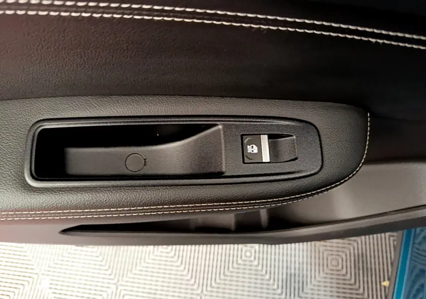 Gros plan sur la poignée intérieure noire avec bouton de verrouillage sur la porte d'une Renault Arkana Techno E-Tech bleu.