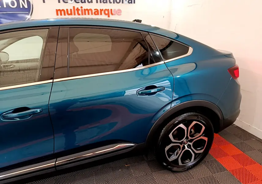 Vue latérale droite du Renault Arkana bleu 2023, mettant en valeur la ligne fluide et les poignées de porte intégrées.