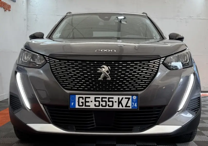 Vue frontale d'un Peugeot 2008 gris foncé avec calandre noire et feux diurnes LED verticaux allumés.