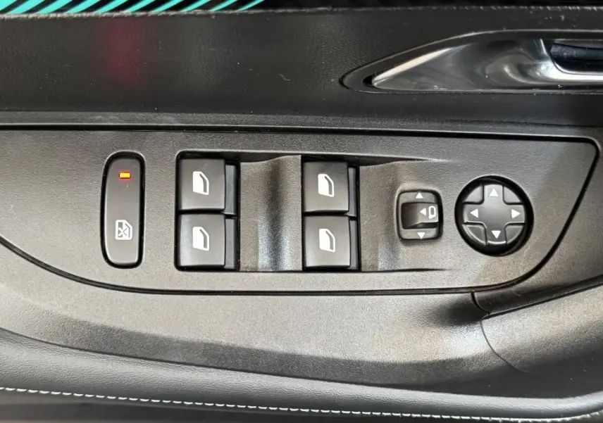 Vue rapprochée des commandes de lève-vitres et réglage des rétroviseurs sur la porte côté conducteur d’un Peugeot 2008 gris foncé.