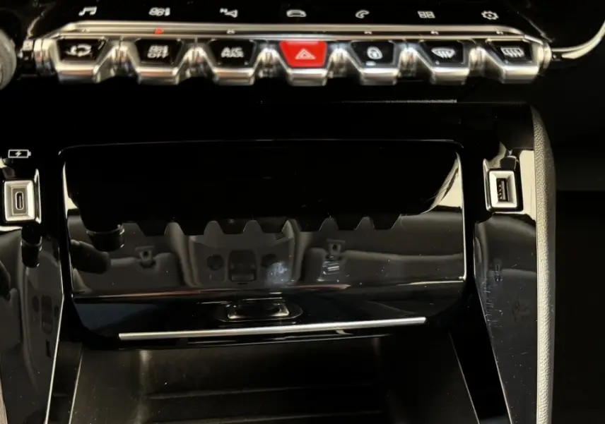 Vue rapprochée de la console centrale noire brillante du Peugeot 2008 avec boutons de commande et ports USB visibles.