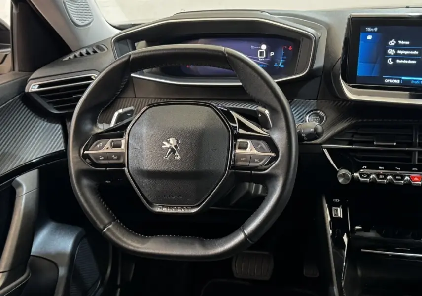 Vue intérieure centrée sur le volant cuir multifonctions et le tableau de bord numérique du Peugeot 2008 gris foncé 2022.