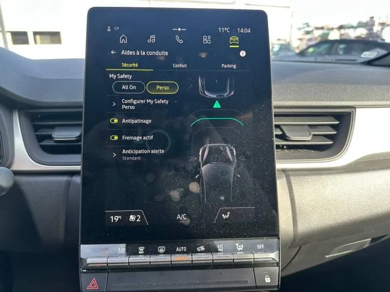 Écran tactile central du tableau de bord du Renault Captur 2025 montrant les aides à la conduite et commandes climatisation.