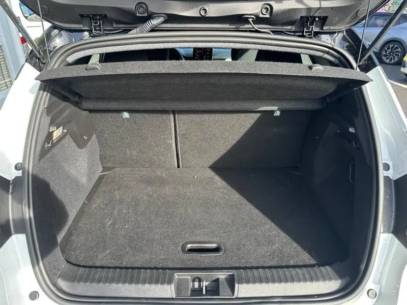 Coffre ouvert vu de l'arrière du Renault Captur blanc nacré/noir étoile, montrant l'espace de chargement vide.