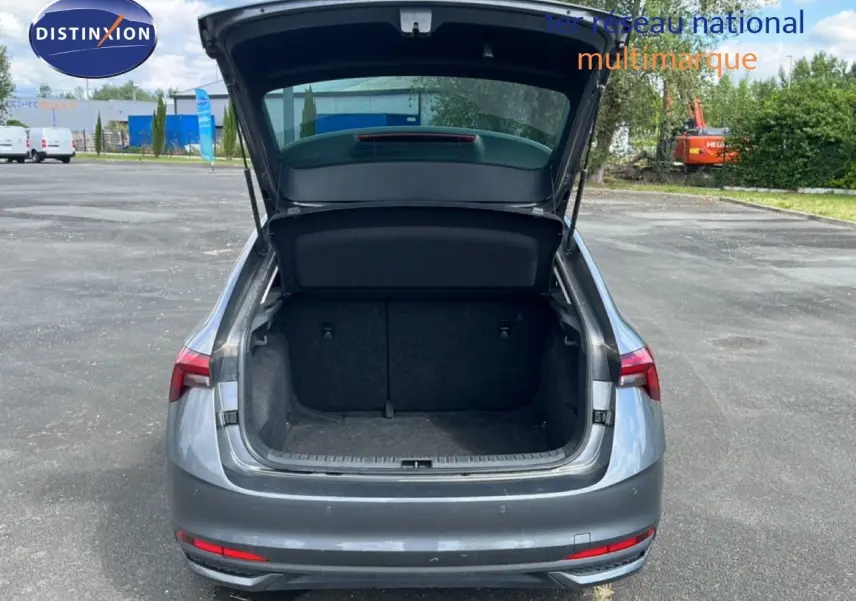 Vue arrière d'une Skoda Scala gris magnétique métal avec coffre ouvert sur un parking extérieur.