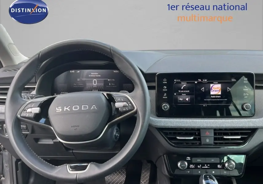 Vue intérieure centrée sur le volant noir et l’écran tactile du tableau de bord d’une Skoda Scala gris magnétique.