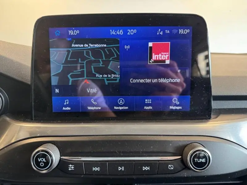 Écran tactile central de la Ford Focus 2021 affichant navigation et radio, avec commandes audio en dessous.