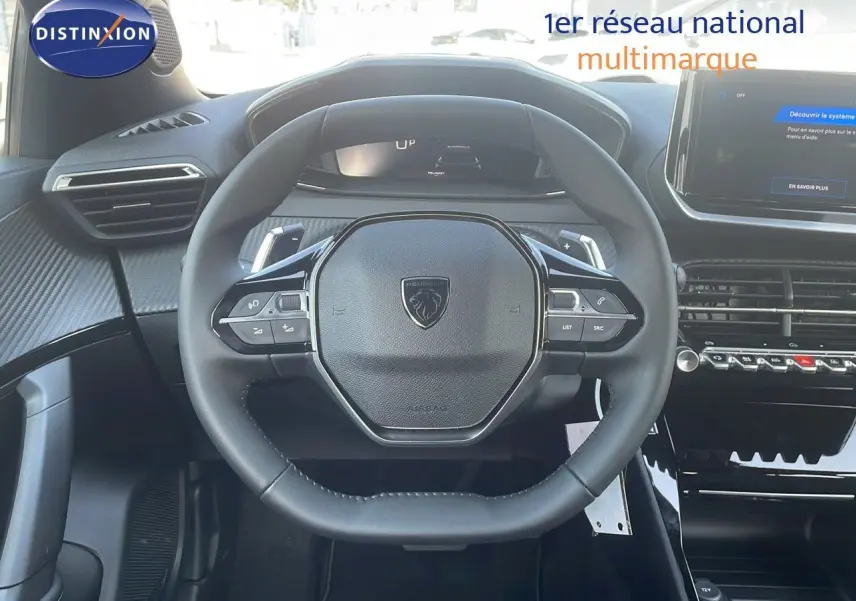 Vue rapprochée du volant cuir noir du Peugeot 2008 Hybrid 136ch Allure 2025 avec tableau de bord digital.