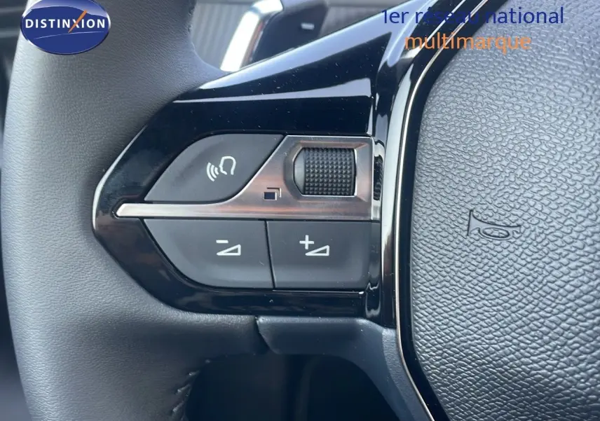 Gros plan sur les commandes de volume et appel au volant noir du Peugeot 2008 Hybrid gris Artense 2025.