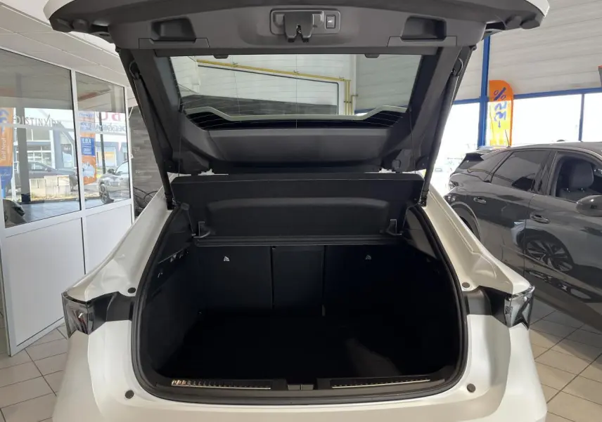 Coffre ouvert vu de l'arrière d'une Renault Rafale blanche 2025 en showroom, avec hayon motorisé visible.